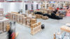 Blick in ein Lager mit Gabelstapler und Packzone an einem automatischen Lager