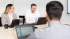 Drei SAP-Profis sitzen mit Laptops an einem Konferenztisch und besprechen Schulungsinhalte