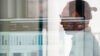 Ein SAP-Experte im Profil durch eine Glasscheibe mit Reflexionen eines Analyse-Bildschirms fotografiert.