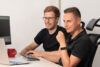 Zwei SAP-Verantwortliche sitzen gemeinsam an einem Schreibtisch mit PC, um SAP EWM Customizing zu lernen.