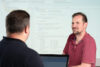 Zwei SAP-Experten sitzen sich gegenüber, um im Rahmen einer Schulung das Customizing im SAP EWM zu besprechen.